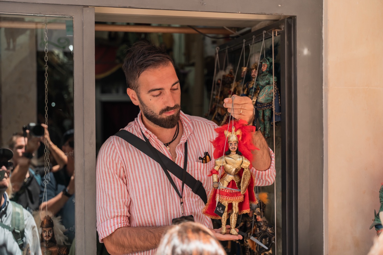 Dario, founder and guide of Hidden Syracuse, holding a traditional Sicilian marionette in an artisan’s doorway in Ortigia