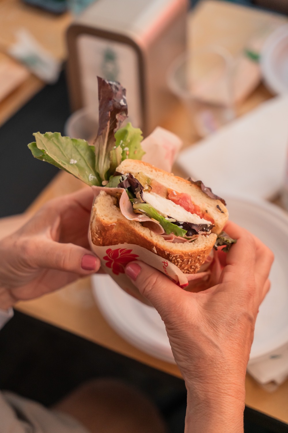 A Sicilian panino filled with same-day mozzarella, prosciutto, tomato and salad leaves, held in both hands